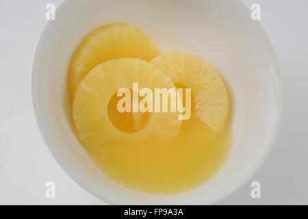 Close up di conserve di fette di ananas e succo di frutta nella ciotola bianco Foto Stock