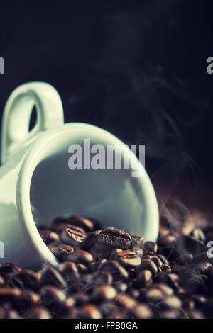 Il caffè. I chicchi di caffè. Tazza da caffè piena di chicchi di caffè. Schizzi di caffè in grani. Tonica immagine. Foto Stock