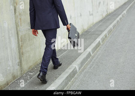 Imprenditore della tuta con valigia passeggiate all'aperto Foto Stock