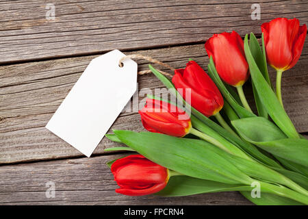 Il giorno di San Valentino tulipani rossi con tag bianco su sfondo di legno Foto Stock