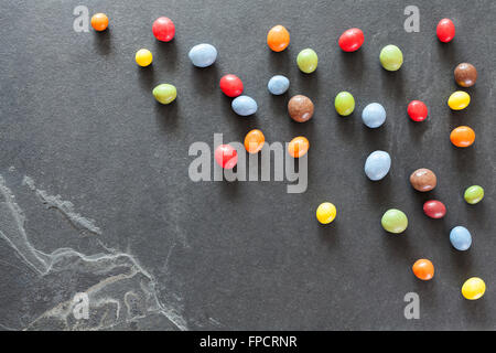 Caramelle colorate su una pietra scura sullo sfondo. Foto Stock