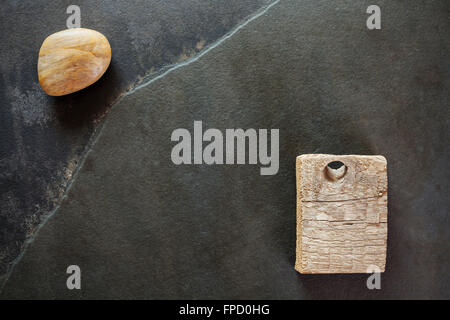 Pietra e un pezzo di legno su ardesia, sfondo astratto. Foto Stock