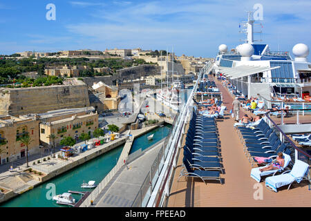 Ponte prendisole della nave da crociera mediterranea di una grande e moderna imbarcazione nel porto e nella città di la Valletta Malta, i passeggeri prendono il sole anziché scendere a terra Foto Stock