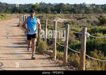 In esecuzione e fare Jogging a La Savina; Pudent Lago. Formentera. Isole Baleari, Spagna, Europa. Foto Stock