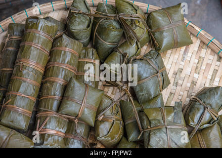 Il vietnamita di riso appiccicoso torte per il Nuovo Anno, Tet. Chiamato banh chung contenenti il riso, la carne di maiale, fagioli mung avvolti in foglie di banano Foto Stock