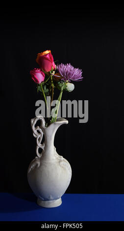 Fiori in vecchio vaso in ceramica bianca su sfondo scuro Foto Stock