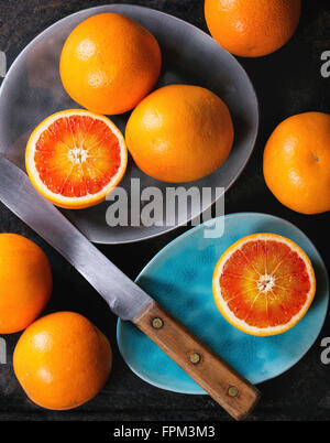 Affettato e tutto il sangue siciliano frutta di arancia sul turchese brillante e grigio di piastre in ceramica su sfondo nero, con kni vintage Foto Stock