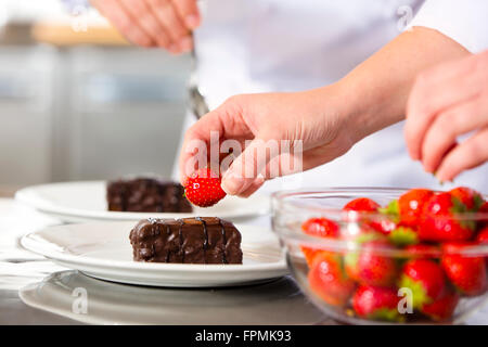 Chef decora dessert torta con salsa di cioccolato in cucina Foto Stock