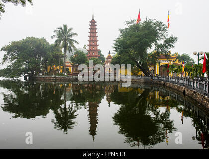 Vista del Buddist Tran Quoc Pagoda e il tempio di fronte Ho Tay Lake in una nebbiosa giornata di gennaio,Hanoi, Vietnam. Foto Stock