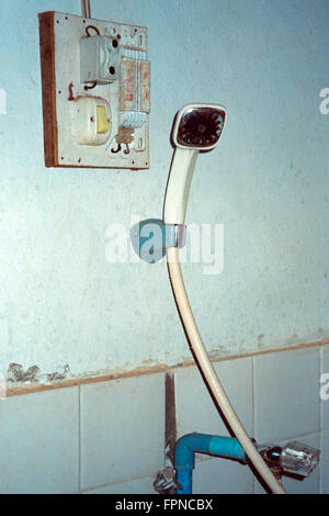 Testa di doccia accanto alla casella di elettricità in hotel economici nel nord del Laos Foto Stock