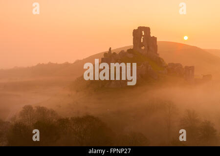 Il sole che tramonta dietro Corfe Castle nel Dorset Foto Stock