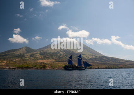 Un Indonesian pinisi schooner vele vicino a Pulau Sangeang, una remota isola vulcanica nei pressi di Komodo in Indonesia. Foto Stock