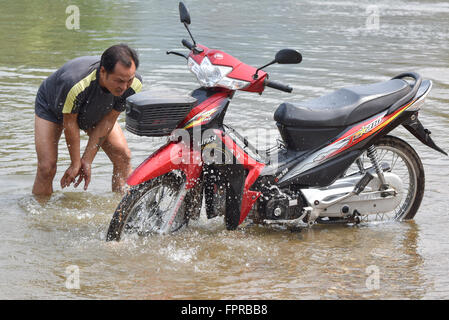 Lavaggio uomo il suo moto nel fiume Mekong Laos Foto Stock
