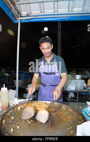 Uomo tailandese per la cottura in un mercato notturno Foto Stock