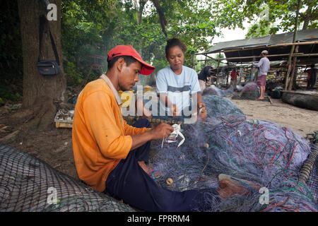 Asia, Tailandia, Trang, pescatori artigianali del villaggio che prendono un granchio da una grande rete da pesca quando lo riparano Foto Stock