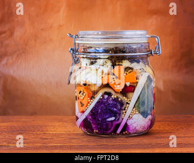 Jar assortiti di messi in salamoia lacto-fermentati sottaceti su un tavolo di legno. Foto Stock