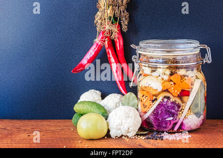 Jar assortiti di messi in salamoia lacto-fermentati sottaceti sul tavolo di legno. Foto Stock