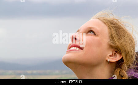 Giovane donna felice cercando in cielo Foto Stock