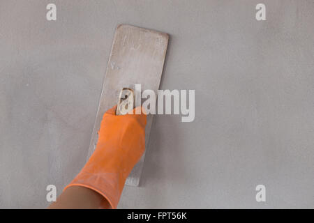 Mano del lavoratore utilizzare cazzuola cemento intonacatura a parete Foto Stock