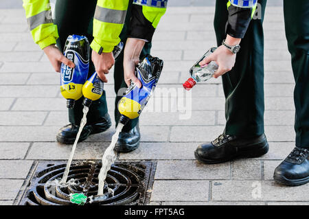 Belfast, Irlanda del Nord. 17 mar 2016 - PSNI gli ufficiali di polizia lo smaltimento di alcole confiscati dai giovani. Foto Stock