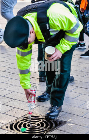 Belfast, Irlanda del Nord. 17 mar 2016 - PSNI gli ufficiali di polizia lo smaltimento di alcole confiscati dai giovani. Foto Stock