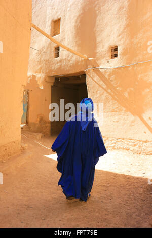 Berber uomo vestito nel tradizionale Tuareg vestiti blu passeggiate attraverso la stretta streest di ksar in Rissani, Marocco Foto Stock