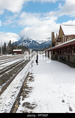 Una donna in piedi a Banff Stazione ferroviaria sulla piattaforma di neve in inverno Foto Stock