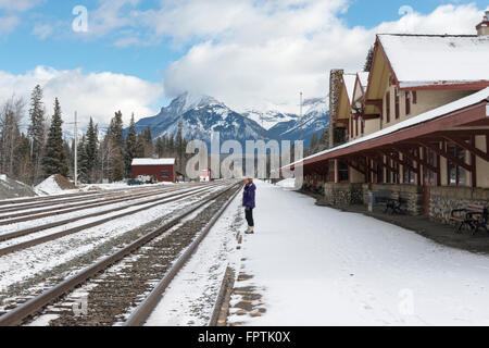 Una donna in piedi a Banff Stazione ferroviaria sulla piattaforma di neve in inverno Foto Stock