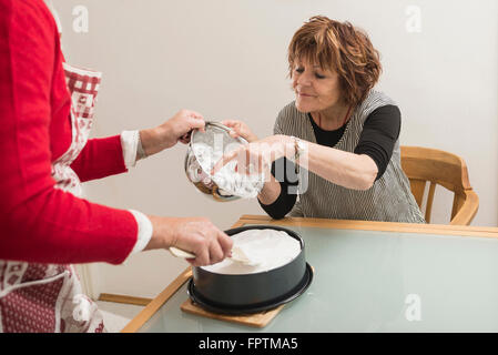 Senior donna meringa roditura con il dito in cucina, Monaco di Baviera, Germania Foto Stock