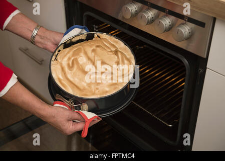 Senior donna tenendo fuori cotta la torta dal forno, Monaco di Baviera, Germania Foto Stock