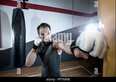 Sportivo facendo forza di formazione mediante punzonatura sul punzone bag in palestra, Baviera, Germania Foto Stock