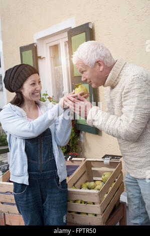 Negozio di femmina Assistant fornisce le mele cotogne al client per annusare, Baviera, Germania Foto Stock