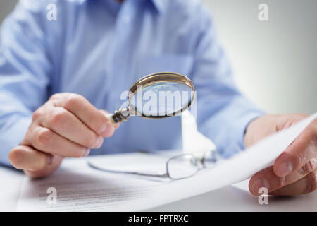 Imprenditore la lettura dei documenti con lente di ingrandimento Foto Stock