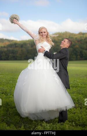 Lo sposo solleva sposa in campo, Ammersee, Alta Baviera, Baviera, Germania Foto Stock