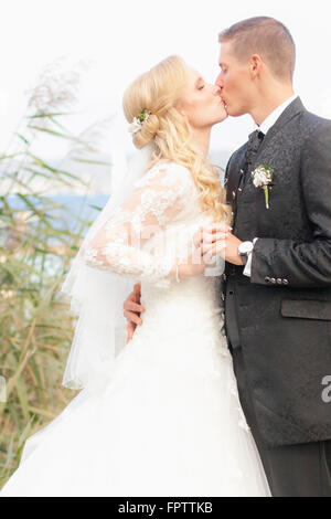 Sposa e lo sposo baciare a Lakeside, Ammersee, Alta Baviera, Baviera, Germania Foto Stock