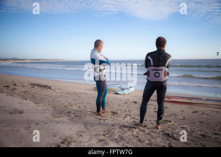 Due surfisti guardando il mare e permanente sulla spiaggia di Viana do Castelo, Regione Norte, Portogallo Foto Stock