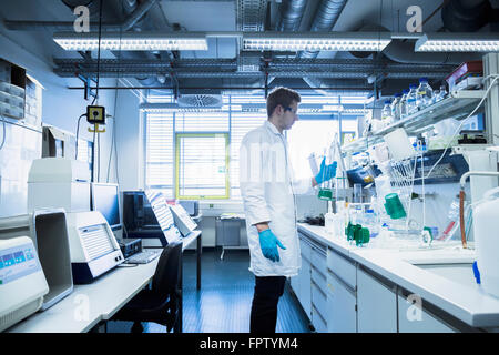 Giovane maschio scienziato che lavora in un laboratorio di farmacia, Freiburg im Breisgau, Baden-Württemberg, Germania Foto Stock