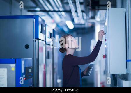 Giovane ingegnere femmina di controllo di una apparecchiatura di manovra nella sala di controllo, Freiburg im Breisgau, Baden-Württemberg, Germania Foto Stock