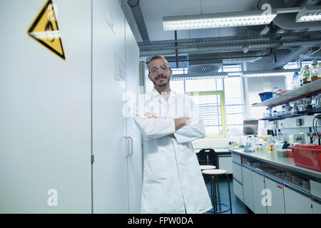 Scienziato in piedi con le braccia incrociate in un laboratorio di farmacia, Freiburg im Breisgau, Baden-Württemberg, Germania Foto Stock