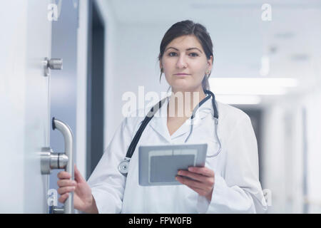 Ritratto di un giovane medico donna utilizzando digitale compressa in ospedale corridoio, Freiburg im Breisgau, Baden-Württemberg, Germania Foto Stock