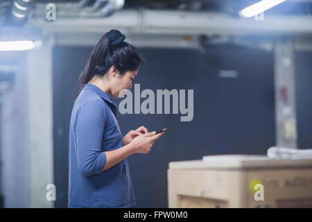 Giovane ingegnere femmina utilizzando una tavoletta digitale in un impianto industriale di Freiburg im Breisgau, Baden-Württemberg, Germania Foto Stock