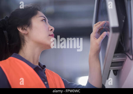 Femmina giovane ingegnere di lavoro sul touchscreen sul monitor di un computer in un impianto industriale, Baden-Württemberg, Germania Foto Stock