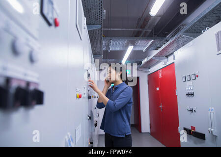 Giovane ingegnere di aggiornamento del pannello di controllo utilizzando il telefono cellulare in un settore di Freiburg im Breisgau, Baden-Württemberg, Germania Foto Stock