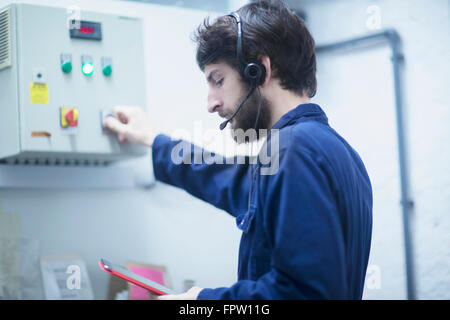 Giovane ingegnere maschio l'aggiornamento di Pannello di controllo digitale compressa nell'industria, Freiburg im Breisgau, Baden-Württemberg, Germania Foto Stock