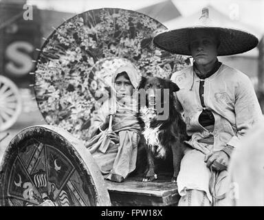 1930s ritratto di un uomo e di una ragazza CIRCUS ESECUTORI CON CANE indossando il tradizionale asiatica ragazza abbigliamento azienda ombrello decorativi Foto Stock