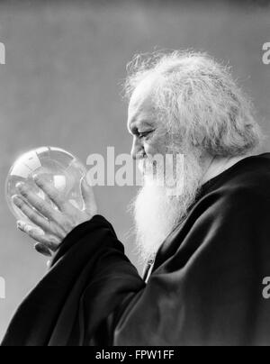 1930s uomo anziano barba bianca tenendo il vetro cristallo SFERA IN MANI MYSTIC FORTUNE TELLER Foto Stock