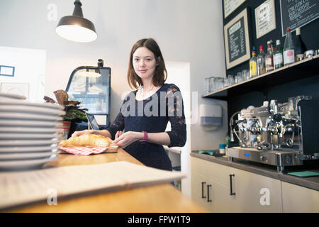 Giovane donna che lavorano nella caffetteria che serve croissant, Freiburg im Breisgau, Baden-Württemberg, Germania Foto Stock