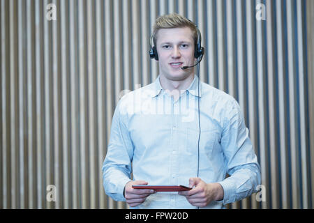 Giovane studente azienda scheda digitale e la lettura in aula magna, Freiburg im Breisgau, Baden-Württemberg, Germania Foto Stock