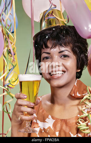 Anni sessanta sorridente americano africano partito donna HAT STREAMERS PALLONCINI TOSTARE PILSNER bicchiere di birra Foto Stock