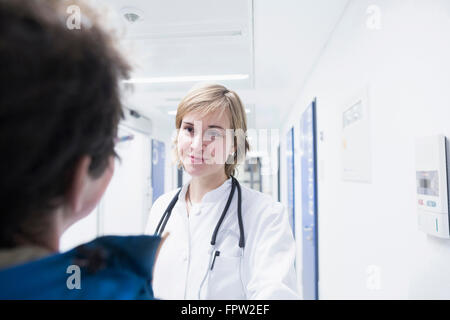 Giovane medico a parlare con il paziente in un ospedale di Freiburg im Breisgau, Baden-Württemberg, Germania Foto Stock